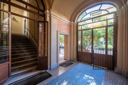 Elegante ingresso di Living Palazzi Storici a Bologna con finestre ad arco, vista sul giardino e classiche porte in legno