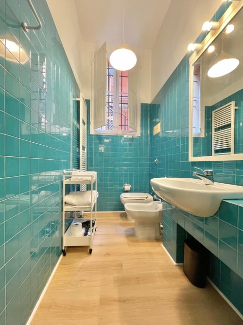 Bagno moderno turchese con pavimento in legno, lavabo, wc e finiture bianche nell'appartamento Living Palazzi Storici