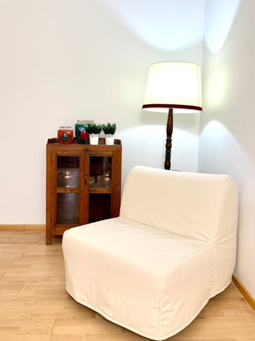 Poltrona color crema con lampada in legno accanto a un antico mobile nell'appartamento Santo Stefano presso Living Palazzi Storici a Bologna