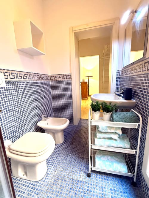 Moderno bagno con mosaico blu, toilette, bidet, lavabo e mobile portasciugamani presso Living Palazzi Storici a Bologna