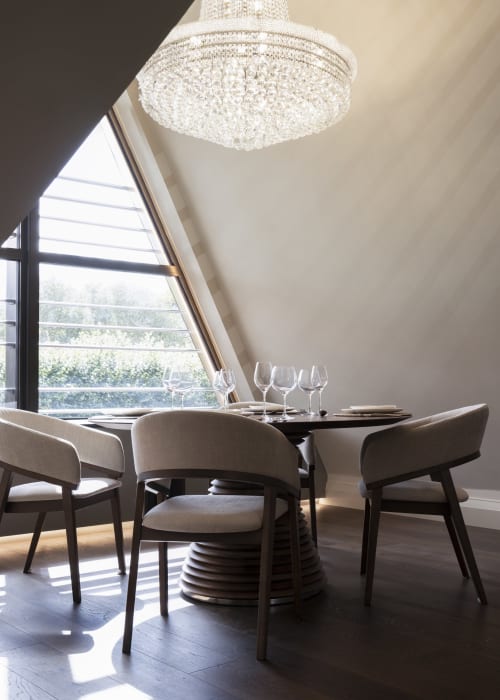 Modern dining area at The Coach House, 100 Banbury Road Oxford, with crystal chandelier, upholstered chairs, and garden views