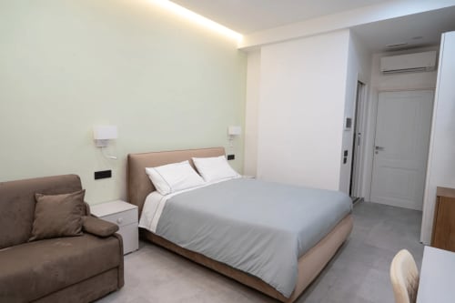 Modern bedroom at Museo19 B&B in Naples with queen bed, brown sofa, and minimalist design