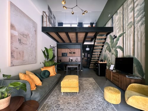 Moderno loft a Milano con camera in mezzanino, divano grigio, accenti gialli, cucina e decori botanici