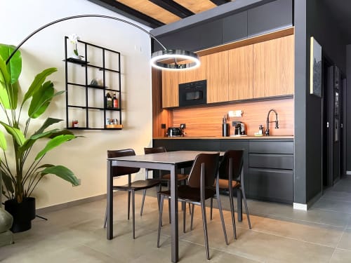 Cucina moderna e zona pranzo del loft Jenner a Nestco Milano con mobili in legno, tavolo e pianta