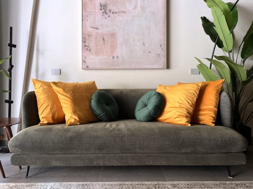 Divano grigio moderno con cuscini oro e teal nell'appartamento The Loft Jenner a Milano, con arte contemporanea e dettagli verdi
