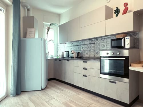 Moderna cucina nell'appartamento Nestco di Milano, con armadi color crema, piastrelle decorate e elettrodomestici in acciaio inox