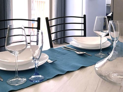 Tavolo da pranzo elegantemente apparecchiato a Nestco Milano con coperto, calici di vino e runner blu