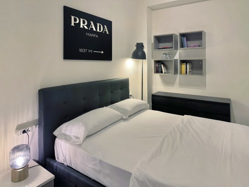 Camera da letto minimalista moderna presso Nestco Milano apartment The Quiet Bausan con letto nero, biancheria bianca e parete Prada Marfa