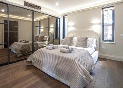 Modern bedroom at 100 Banbury Road Oxford B&B with mirrored wardrobe, striped bedding, and wooden flooring