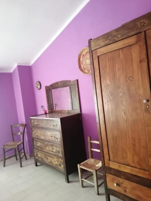 Camera da letto viola brillante al B&B Daddanca di Ales con comò in legno, specchio e armadi