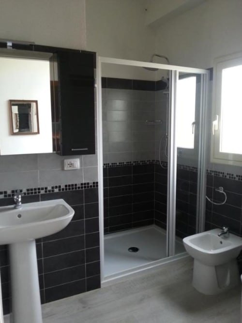 Bagno moderno a B&B Daddanca ad Ales con piastrelle nere e grigie, doccia walk-in, lavabo con piedistallo e bidet