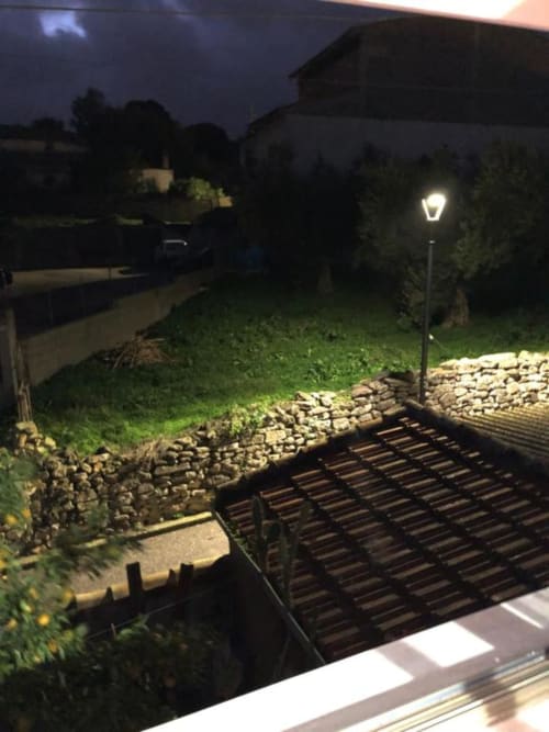 Vista notturna della corte interna del B&B Daddanca a Mogoro con percorso illuminato, muri in pietra e rigogliosa vegetazione