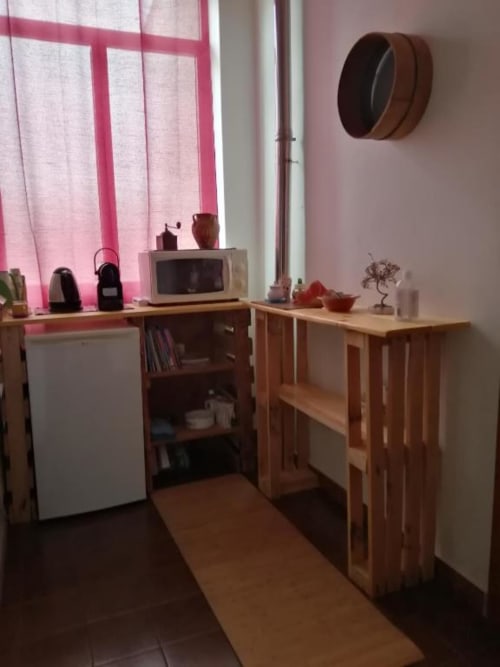 Camera da letto B&B Daddanca ad Ales con scrivania in legno, microonde, finestra con cornice rosa e vista sulla corte interna