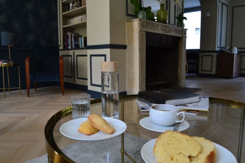 Élégant salon de L'ODE A PIERRE à Dax avec viennoiseries, café et eau sur table en verre