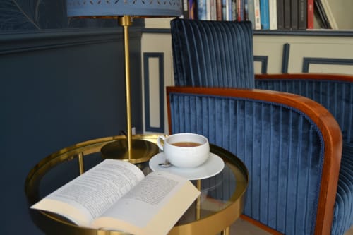 Coin lecture à L'ODE A PIERRE : livre ouvert, tasse de café, table en laiton et chaise bleue à Dax