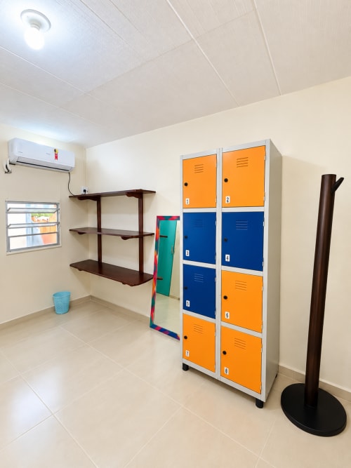 Quarto compartilhado do Hostel New Ipanema com armários coloridos, prateleiras escuras, ar condicionado e piso em azulejos no Rio de Janeiro