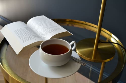 Livre ouvert et tasse de thé sur une table en laiton à L'ODE A PIERRE, boutique hôtel à Dax, France