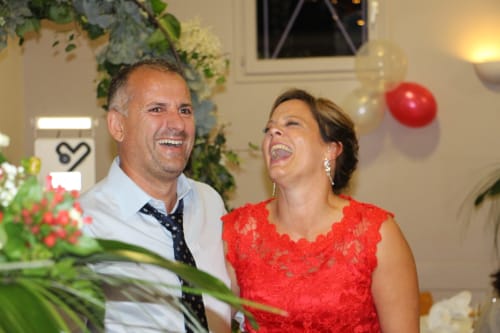 Couple riant aux Gîtes De Flaubert à Morville le Héron, homme en chemise bleue et cravate, femme en robe rouge lors d'une célébration