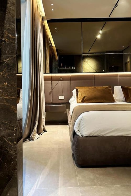 Camera lussuosa da Donna Filomena con letto king, cuscini dorati, illuminazione moderna e dettagli in marmo