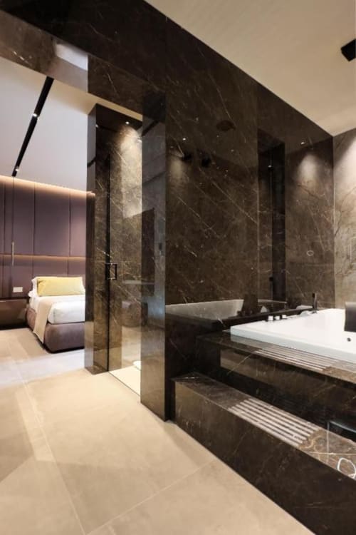 Bagno di lusso moderno nella suite Donna Filomena con marmo scuro, doccia in vetro, divano bianco e vista sulla città dalla terrazza