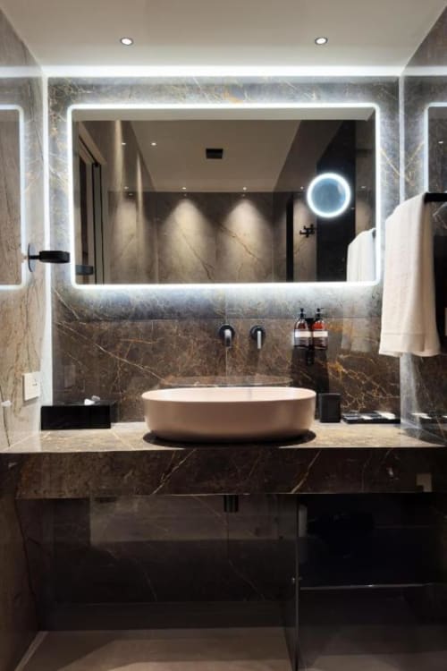 Lussuoso bagno moderno con specchio illuminato a LED, pareti in marmo, lavabo bianco rotondo e vista sulla città a Donna Filomena, Italia