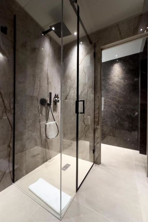 Lussuosa cabina doccia moderna con pareti in marmo, soffione pioggia e box in vetro nella suite Donna Filomena.