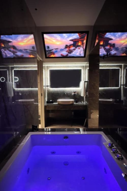 Lussuoso bagno moderno a Donna Filomena con specchio illuminato, vasca idromassaggio blu, doppio lavabo e vista al tramonto
