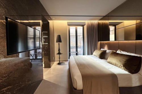 Camera da letto lussuosa con TV, dettagli oro, vista sulla terrazza e finiture in marmo moderno