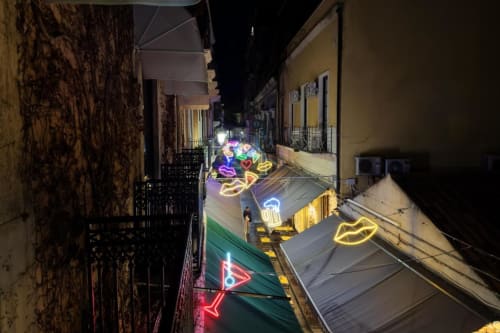 Vicolo illuminato al neon presso Donna Filomena Luxury Suites, boutique hotel italiano con colorati simboli di cuore e accogliente facciata dell'edificio