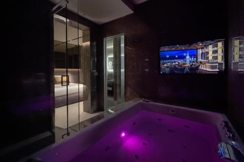 Suite spa lussuosa da Donna Filomena con vasca idromassaggio illuminata di viola, doccia in vetro, camera da letto e TV a parete
