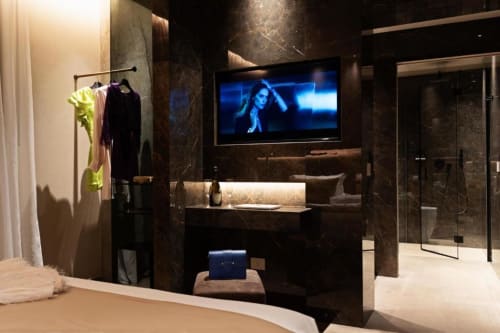 Lussuosa camera d'hotel Donna Filomena con muri in marmo scuro, TV a schermo piatto, vanity moderno, doccia in vetro e eleganti finiture nere