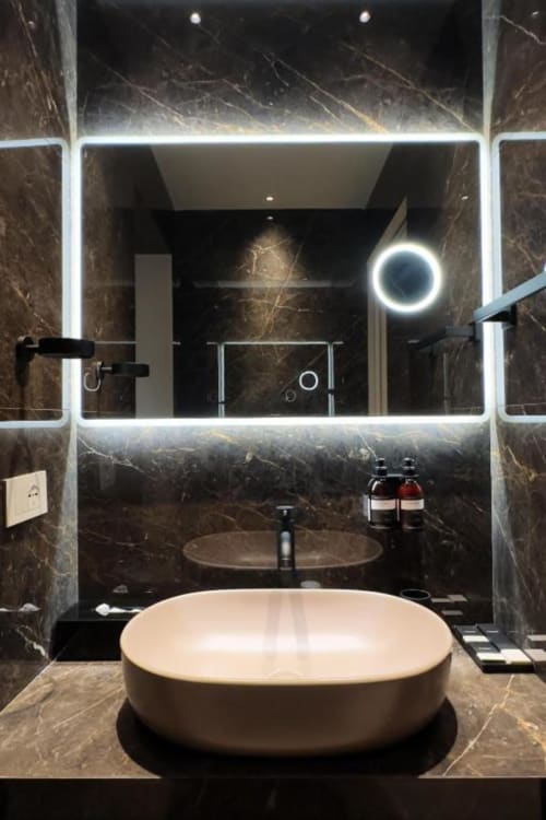 Lussuoso bagno moderno con pareti in marmo, specchio illuminato a LED, vasca indipendente beige e doppio lavabo da Donna Filomena Luxury