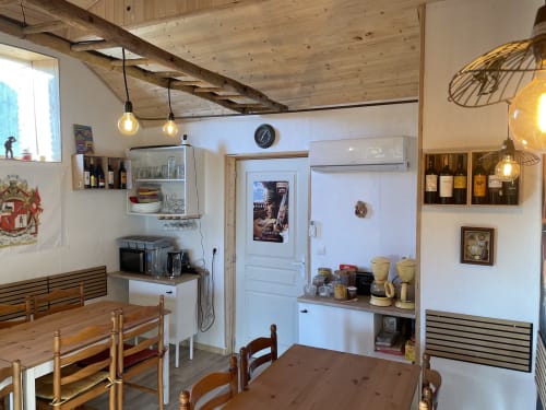 Coin repas cosy du gîte Le Petit Moulin à Pouzauges, avec poutres en bois et étagères de rangement pour vins