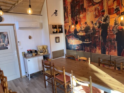 Salle à manger rustique de la maison d'hôtes Le Petit Moulin à Pouzauges avec table en bois, affiche de jazz vintage et luminaires suspendus