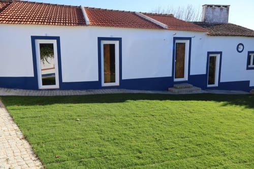 White and blue facade of Herdade Do Vidigal hotel in Montemor-o-Novo with manicured lawn and terracotta roof