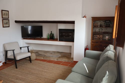 Modern living room at Herdade Do Vidigal with fireplace, flat-screen TV, gray sofa, and mid-century furniture,