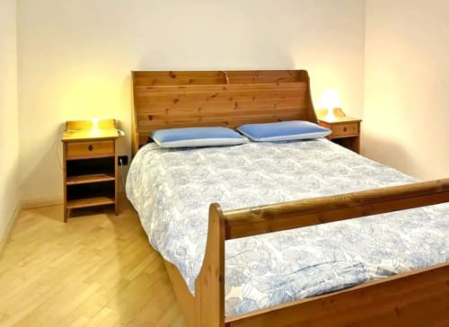 Camera da letto in legno con due letti, cuscini blu, comodini con lampade e pavimenti in parquet a Debby Siusi house