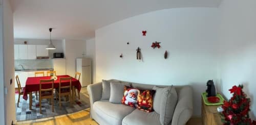 Appartamento decorato per le festività presso la casa di Debby a Siusi con divano beige, tavolo da pranzo rosso e ornamenti natalizi