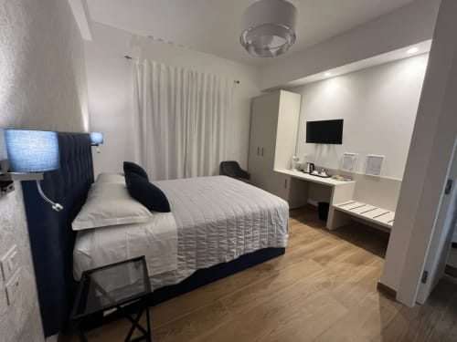 Camera moderna della Maritza Guest House a Roma con letto, scrivania, TV e pavimento in legno