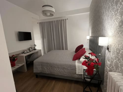 Camera moderna alla Maritza Guest House di Roma con letto matrimoniale, dettagli rossi, TV, scrivania e carta da parati decorativa