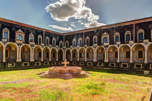 Storico cortile italiano con colonnato ad archi, fontana centrale e finestre ornamentali presso Donna Filomena Luxury Suites