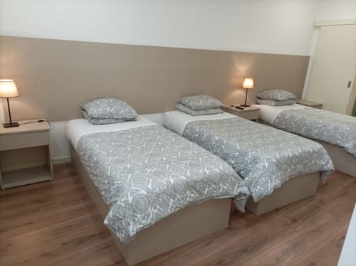 Quarto triplo na Hospedaria Londres no Porto com três camas, roupa de cama cinzenta estampada e mesas laterais com candeeiros