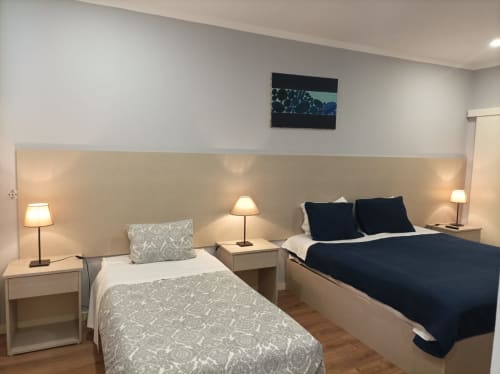Hospedaria Londres Porto: quarto triplo com duas camas, TV de tela plana, luminárias de cabeceira e cabeceira bege.