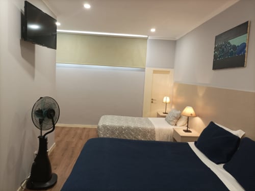 Quarto moderno da Hospedaria Londres Porto com camas geminadas, TV, ventilador e decoração minimalista
