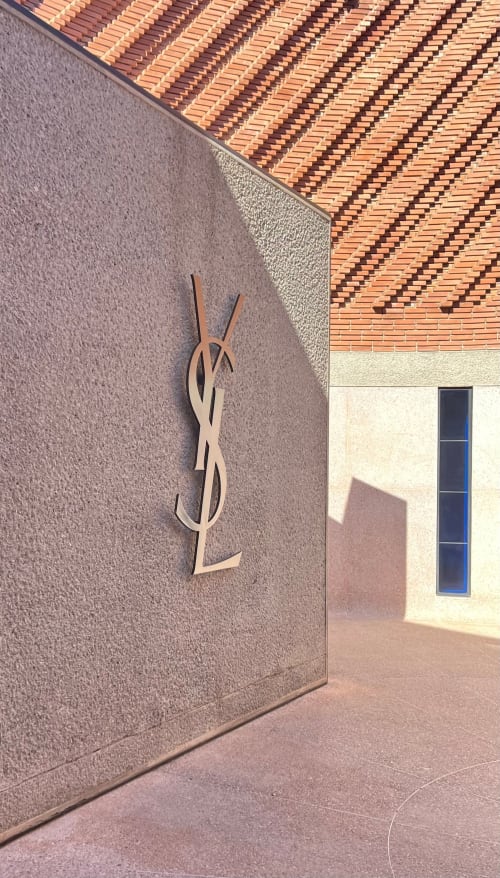YSL logo on purple wall at Riad Casa Angelo in Marrakech, modern architectural detail with terracotta roof