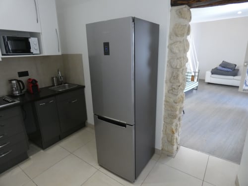 Cuisine moderne dans un appartement de Nanterre avec réfrigérateur en acier inoxydable et placards noirs
