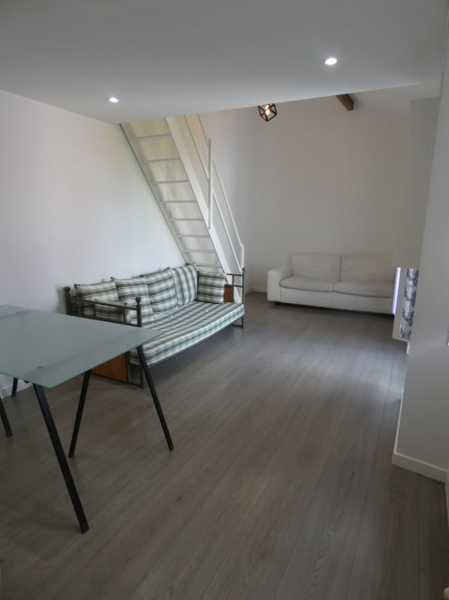 Séjour de type mezzanine Sci Ludji à Nanterre avec canapé rayé, sofa gris et parquet