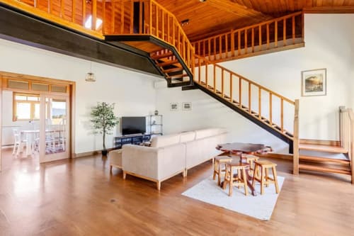 Modern cottage living room in Chaves with wooden staircase, white sofa, TV, and wooden flooring at Casa dos Vasconcelos B&B
