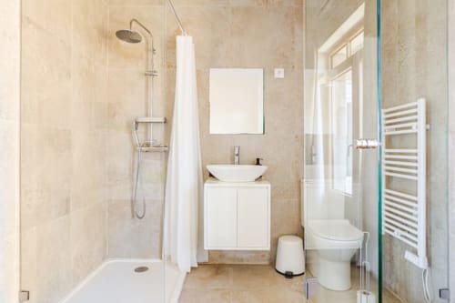 Modern bathroom in Casa dos Vasconcelos cottage in Chaves with shower, vessel sink, toilet, and heated towel rack