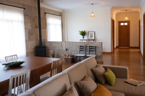 Modern cottage living area in Casa dos Vasconcelos, Chaves featuring beige sofa, wooden dining table, and fireplace